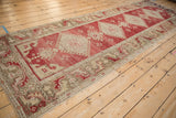 Angled view of a distressed Oushak runner with an abrashed red field and ivory medallions.