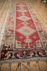 Long perspective view of a vintage Oushak runner's geometric medallions and borders.