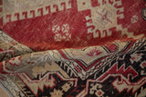 A fold revealing the low pile and ram's horn style border of a distressed Oushak runner.