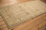 Vintage distressed Oushak runner corner displaying a checkered overlay, cross-hatch border, and surface pile wear.