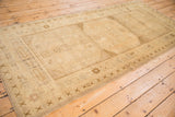 Oushak rug edge with cross-hatch border and primitive floral motif, showing low pile.