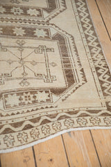 Vintage distressed Oushak runner detail: geometric guls and meandering brown border in sand tones.