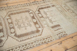 Distressed vintage Oushak runner with geometric guls, meandering vine border, and faded beige brown tones.
