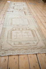 Geometric guls and meandering border details on a distressed Oushak runner in beige, sand, and pale rose.