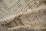 Folded vintage distressed Oushak rug with geometric guls and time-softened neutral palette.