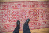 Distressed Kurd runner featuring geometric motifs in dusty fuchsia, tangerine, and ivory, with boots.