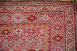Upper corner of distressed Kurd runner with geometric guls and fuchsia, orange florals.