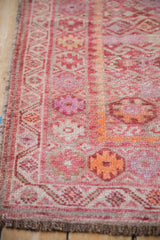 Distressed vintage Kurd runner's side, showing dusty fuchsia geometric guls and intact selvage.
