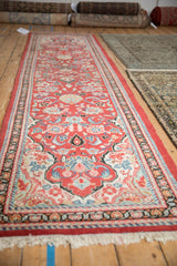 Angled view of a vintage Arak runner highlighting its long, repeating brick red floral pattern.