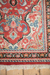Corner detail of a vintage Arak rug showing the floral vine border and ivory fringe.