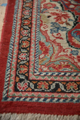 Detailed view of the hand-knotted pile and meandering vine border on the vintage Arak rug.