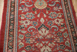 Detailed texture of a vintage Arak runner's red floral field and black meandering vine border.