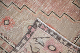 Distressed Oushak runner close-up with worn dusty mauve pile, zigzag pattern, and woven selvage.