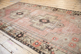 Distressed Oushak rug border with meandering plant motif and muted mauve field.