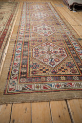 Antique Serab runner's geometric serpent border and worn selvage in red, blue, and camel.