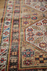 Antique Serab runner with a geometric border and camel field, featuring colorful pinwheel floral motifs and wear.