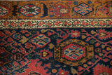 Madder red palmettes, hexagonal forms on a navy Bijar rug with ivory border.
