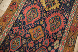 Bijar rug detail: madder root red palmettes, navy blue field, and dusty gold border.