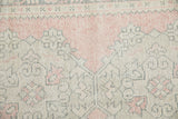 Distressed Oushak rug detail with dusty blush, ivory, and charcoal geometric motifs.