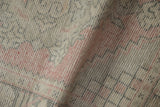 Distressed vintage Oushak rug's pile texture reveals wear, faded blush, ivory, and charcoal.
