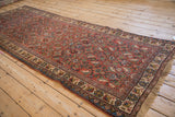 Vintage Bijar runner viewed from an angle, highlighting the allover Herati pattern on its brick red field.