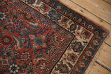 Angled view of a vintage Bijar runner's corner, showing the worn selvedge and intricate floral borders.