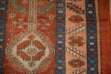 Serrated leaf border and geometric medallion detail on an antique Persian Heriz rug in cherry red and blue.