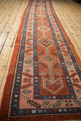 Angled perspective of a long antique Heriz runner with its vivid red, pink, and blue geometric pattern.