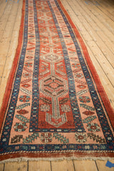 Angled view of an antique Heriz runner's interconnected medallions on its abrashed cherry red field.