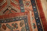 Folded corner of an antique Persian Heriz rug showing the hand-knotted texture and secure side cord.