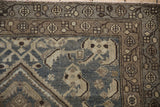 Checkered flower and vine borders on a distressed vintage Hamadan rug in slate blue and silver tones.