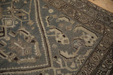Corner detail on a distressed Hamadan rug with a Herati spandrel and checkered flower border.