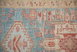 Detail of sharp stepped contours and geometric blossoms in dusty red on a powder blue field.