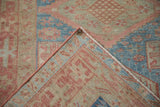 A folded corner on a vintage Persian rug reveals the tight back weave and dusty red side cord.