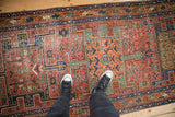 Antique Heriz runner's geometric turtle motifs with brick red, navy, and ochre hues.