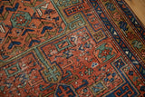 Antique Heriz rug runner's brick red field with sapphire blue and jade geometric patterns.