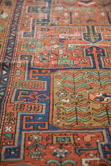 Antique Heriz rug detail showing geometric and stylized plants in brick red, sapphire blue.