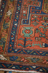 Antique Heriz runner's brick red field with sapphire blue border and stylized motifs.