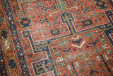Antique Heriz runner's geometric patterns with brick red, sapphire blue, and evident pile wear.