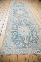Distressed Bakhtiari runner's fringed end with blue, blush, rust floral motifs, showing mostly even wear.