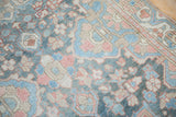 Soft floral patterns in dusty blue, rose, and ivory on a distressed Bakhtiari rug.
