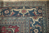 Corner detail of a vintage Khorassan rug's Samovar Turtle border in dusty blue and ivory.