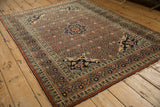 Perspective view highlighting the rust field and navy blue medallion of an antique Haji Jalili Tabriz rug.