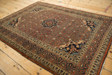 Formal composition of an antique Tabriz rug with a rust Herati field and dark navy medallion.