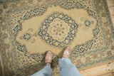 Vintage Tabriz rug with beige field, navy blue scalloped medallion, and meandering arabesque border.