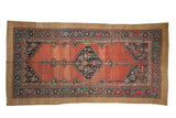 Antique Hamadan runner with a navy diamond medallion on an abrashed red field surrounded by serrated leaf borders.