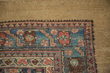 Low pile texture and serrated leaf border detail on a hand-knotted antique Hamadan rug corner.