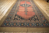 Angled view of an antique Hamadan runner, highlighting its camel border and abrashed ruby-red field.