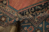 Folded view of an antique Hamadan rug's serrated leaf border and hand-knotted pile.