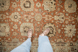Decorative wear on a vintage Tabriz carpet showing terracotta, sand, and pale blue palmettes.